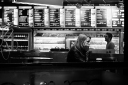 A young woman looking bored on her own in a London cafe at night